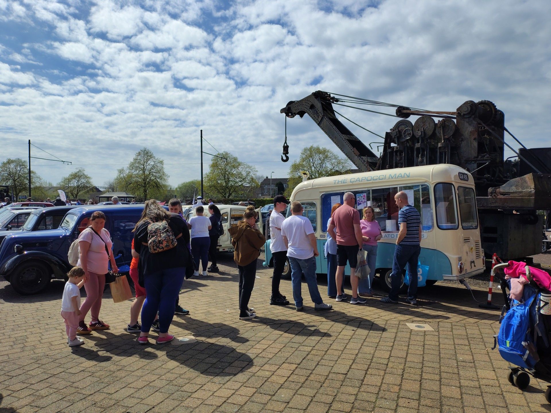 People queue at a vintage-style ice cream van at Summerlee Museum on a sunny day.